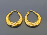 deux paires de boucles d'oreilles créoles dorées sur un fond noir