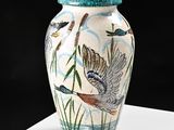 a vase with a bird design on it sitting on a table