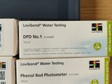 three boxes of water testing equipment sitting on top of a wooden table