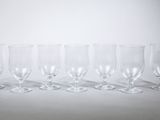 six empty wine glasses lined up in a row on a white surface