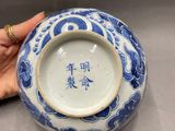 someone is holding a blue and white vase with chinese writing on it