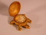 a gold turtle shaped clock sitting on a white surface