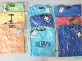several different colored t - shirts in plastic bags on a white surface