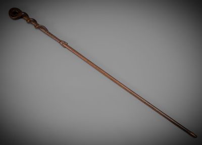 an old wooden stick with a metal handle on a gray background