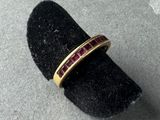 a close up of a gold ring with a red stone in it