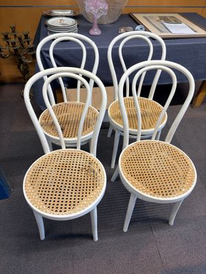 quatre chaises blanches placées les unes à côté des autres dans une pièce