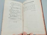 someone is holding an open book in their hand on a table
