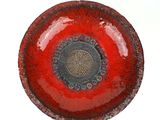 a red bowl with a black center on a white surface