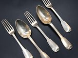 a set of four silverplated forks and spoons on a black background