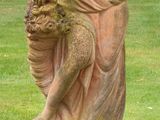 a statue of a woman sitting on a pedestal in the grass