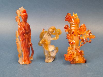 trois figurines sculptées représentant des personnages asiatiques sur un fond bleu