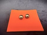 a pair of silver ball stud earrings sitting on top of an orange piece of paper