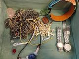 une boîte en bois contenant divers objets, notamment une montre, des bracelets et d'autres articles