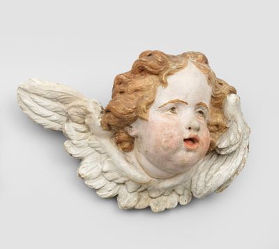 une tête d'ange blanche accrochée au mur, à côté d'un mur blanc
