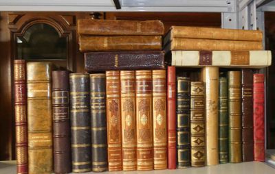 de nombreux livres anciens sur une étagère à côté d'une horloge