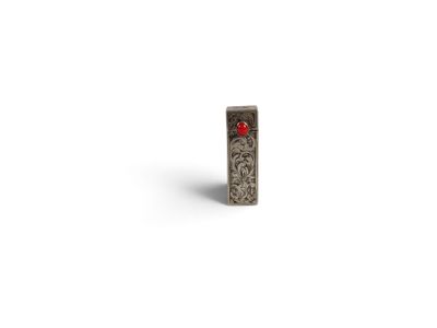 un petit objet en argent orné d'une fleur rouge