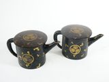 two black and gold teapots with gold designs on them