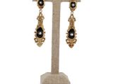 une paire de boucles d'oreilles noires et dorées posée sur un présentoir