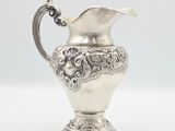 an antique silver plated pitcher on a white background