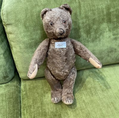 un ours en peluche assis sur un canapé vert