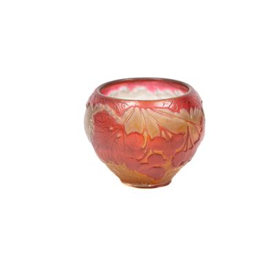 un vase rouge et doré posé sur une surface blanche