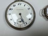 a silver pocket watch sitting next to a silver pocket watch