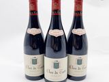 trois bouteilles de vin rouge posées l'une à côté de l'autre sur une surface blanche