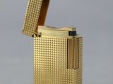 un gros plan d'un briquet doré posé sur une surface blanche