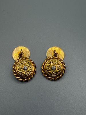 une paire de boucles d'oreilles en or et diamants posées sur une surface grise