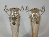 two silver vases that are sitting on a table