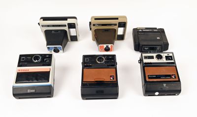 six polaroid cameras are lined up in a row on a white surface