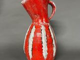 a red and white vase sitting on a gray surface
