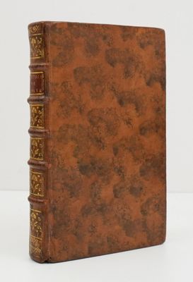 un vieux livre à la couverture marron posé sur une table blanche