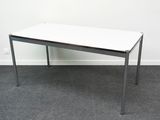 une table blanche avec un plateau noir posée sur un sol recouvert de moquette