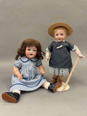 deux poupées en porcelaine représentant un garçon et une fille assis l'un à côté de l'autre