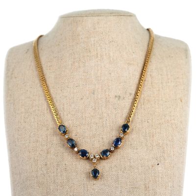 un collier en or orné de pierres bleues et de perles, posé sur un mannequin