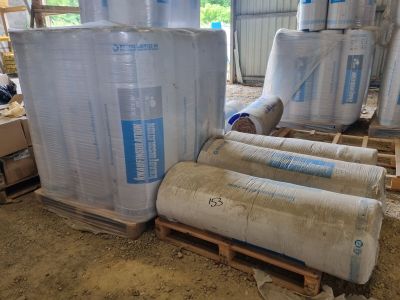 de nombreux rouleaux de plastique empilés sur des palettes dans un entrepôt