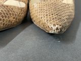 pair of brown snakeskin slippers on a table with a black background