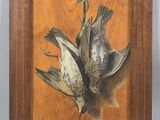 painting of two dead birds in a wooden frame on a table