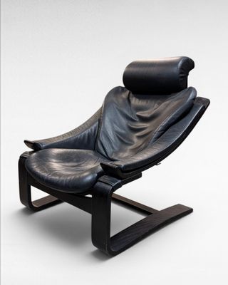 black leather recliner chair with foot rest and foot rest in front of a white background