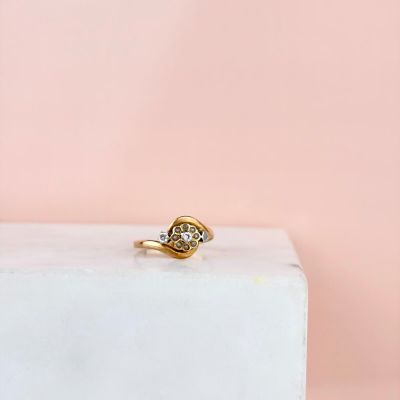 un gros plan d'une bague en or et diamants posée sur un bloc de marbre