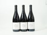 trois bouteilles de vin sont alignées sur une surface blanche