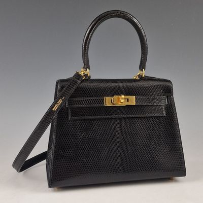 un sac à main en cuir de lézard noir avec des finitions dorées sur la poignée