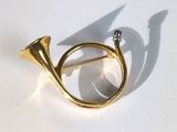 une broche en forme de corne en or, sertie d'un diamant