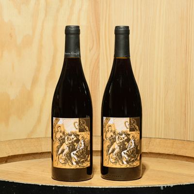 two bottles of wine sitting on top of a barrel next to each other