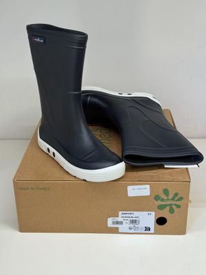 des bottes de pluie noires à semelles blanches posées sur une boîte en carton