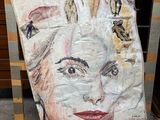peinture représentant le visage d'une femme sur une feuille de papier posée devant une commode
