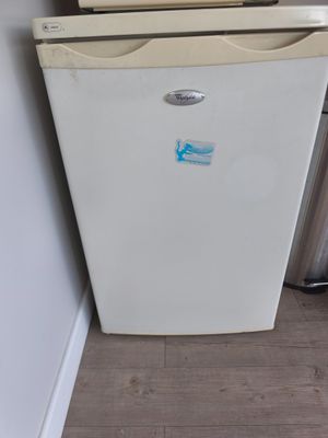 un petit réfrigérateur blanc dans le coin d'une pièce
