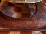a metal bowl on top of a wooden table on a checkered floor