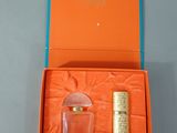 an orange box containing a bottle of perfume and a lighter